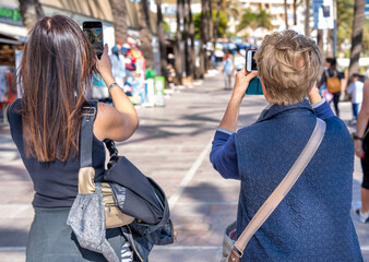 Sticker - Two women of different ages together photographing city street life on a sunny day