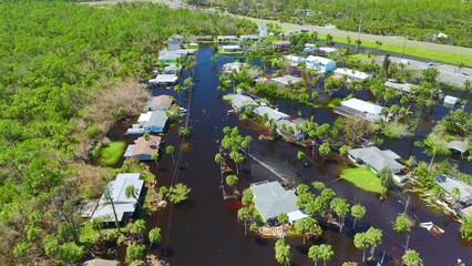 Wall Mural - Kayak boat floating on flooded street surrounded by hurricane Ian rainfall flood waters homes in Florida residential area. Consequences of natural disaster