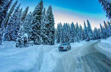 Wall Mural - Car speeds up along a winter mountain road surrounded by snow