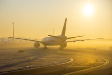 Airplane Taxing On Taxiway In Orange Fog Conditions. Yellow Taxi Line