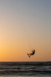Black silhouette of a man on a wakeboard taking off over the Mediterranean Sea in Israel against the backdrop of sunset and horizon