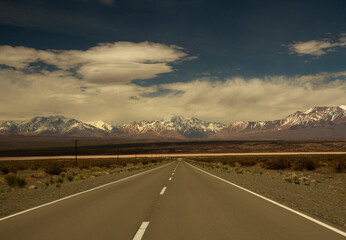 Wall Mural - Traveling along the asphalt highway across the arid desert and into the Andes cordillera, under a beautiful blue sky with clouds.