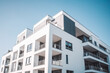 © VisualProduction - Modern multistory apartment building with white walls and parking spaces in front. Generative AI
