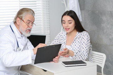 Sticker - Senior doctor consulting patient at white table in clinic