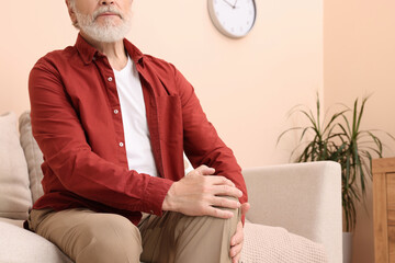 Wall Mural - Senior man suffering from pain in his knee at home, closeup. Arthritis symptoms