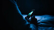Illustration of a person’s arm and hand holding a smart phone in a dark bedroom, in bed. Blue light, insomnia, wellness, health, social media addiction, created with generative AI technology