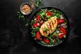 Fototapeta Kawa jest smaczna - Chicken breast fillet grilled and fresh vegetable green salad with arugula, tomatoes and olives on black background, healthy food, mediterranean diet, top view