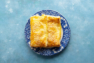 Puff pastry dough. Folded baked puff pastry pie in a plate, blue background