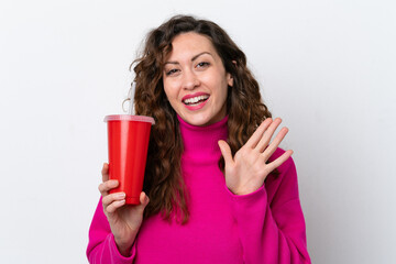 Wall Mural - Young caucasian woman drinking soda isolated on white background saluting with hand with happy expression