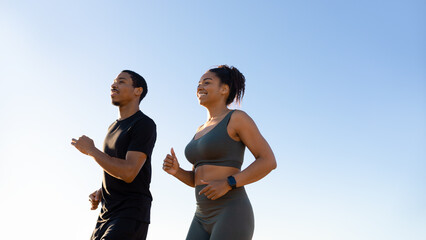 Glaad millennial african american woman and man in sportswear running on sky background