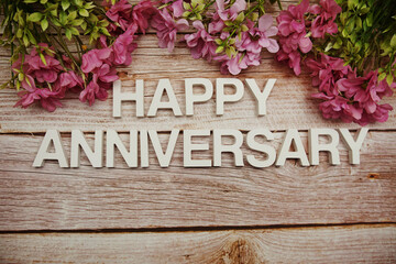 Poster - Happy Anniversary alphabet letters with flowers frame on wooden background