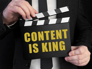 Poster - A businessman holds up a сlapperboard with text CONTENT IS KING