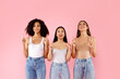 © Prostock-studio - Look upward. Happy three multiethnic women pointing up, standing over pink studio background