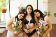 Female friends holding flowers in their underwear and smiling