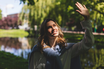 Sticker - Beautiful woman smiling and hide from sun by hand at park at sunny day. Outdoor portrait of a smiling curly blonde girl. Happy cheerful girl laughing at park, look fashion and show toothy smile.