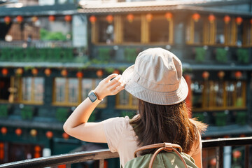 woman traveler visiting in Taiwan, Tourist with hat and backpack sightseeing in Jiufen Old Street village with Tea House background. landmark and popular attractions near Taipei city. Travel concept