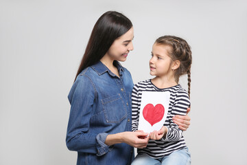 Canvas Print - Happy woman with her daughter and handmade greeting card on light grey background. Mother's day celebration