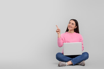 Sticker - Smiling young woman with laptop on grey background, space for text