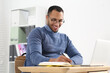 © New Africa - Smiling African American man writing in notebook at wooden table