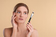 © New Africa - Woman with swatch of foundation holding makeup brush on beige background. Space for text