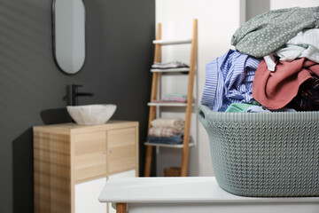 Wall Mural - Laundry basket filled with clothes on table in bathroom, closeup. Space for text