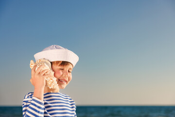 Poster - Happy child listen seashell on the beach