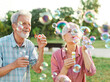 © Lumos sp - woman man senior couple  together elderly active happy retirement bubble soap blowing fun blow vitality bonding park outdoor leisure park fun