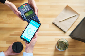 Poster - Top view of hands of clerk with terminal and client with smartphone over counter desk during contactless payment for food and drinks