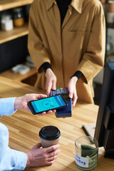Poster - Close-up of cafe clerk in uniform holding terminal during contactless payment while female client with smartphone paying for coffee