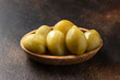 Homemade fermented green tomatoes served in wooden bowl