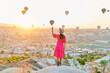 © Goffkein - Free carefree happy inspired girl traveler walking in valley in Anatolia, Kapadokya. Touching flying air balloons at beautiful destination in Nevsehir, Goreme