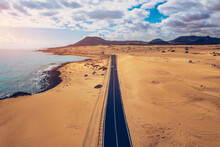 Fuerteventura, Corralejo Sand Dunes Nature Park. Beautiful Aerial Shot. Canary Islands, Spain. Aerial View Of An Empty Road Through The Dunes At The Sunset. Fuerteventura, Canary Islands, Spain.