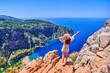 © Goffkein - Free carefree girl traveler with open arms stands on hill rock over blue sea bay in Turkey, butterfly valley