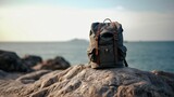 Fototapeta  - Backpack on a big rock near the beach and sea in late afternoon - AI Photography