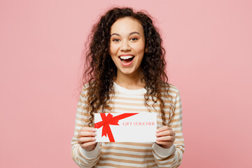 Wall Mural - Young surprised shocked woman of African American ethnicity she wear light casual clothes hold gift certificate coupon voucher card for store isolated on plain pastel pink background studio portrait.