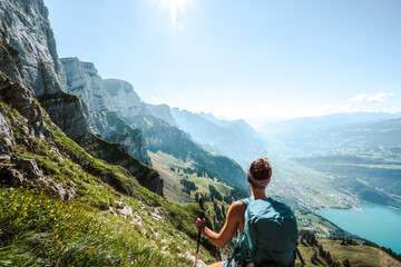 Wall Mural - Sporty woman enjoys epic view on the Churfürsten mountain range from hike trail below steep rock wall. Schnürliweg, Walensee, St. Gallen, Switzerland, Europe.