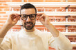 © ADDICTIVE STOCK - Cheerful man choosing eyeglasses in shop
