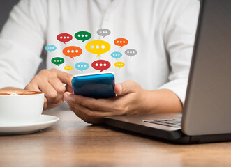 Wall Mural - close-up of hands using mobile phone with colorful chat icons on application communication digital