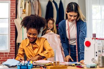 Portrait of young african american woman and young girl fashion designer stylish sitting and working with color samples.Attractive two designer girl work with colorful fabrics at fashion studio