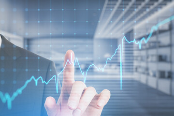 Poster - Close up of businessman hand pointing at growing blue financial forex chart on blurry office interior background. Stock, economy, market and trade concept. Double exposure.