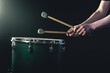 © puhimec - A man plays a musical percussion instrument with sticks on a dark background.