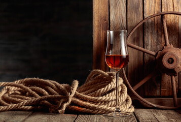 Wall Mural - Snifter with rum, cognac, or whiskey on an old wooden background. Copy space.