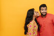 © Drobot Dean - Smiling indian couple gossiping isolated over yellow background