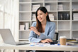 © bongkarn - Inspired Asian businesswoman looking at her laptop screen and working at her desk