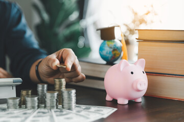 Hand putting coin on stack with piggy bank. Concept of saving money for a scholarship to study abroad at a university level. Financial planning accounting ideas for future education.
