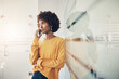 © Flamingo Images - Young businesswoman leaning against a glass wall and talking on her phone