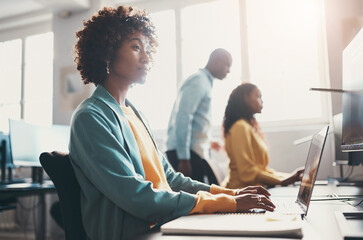 Young businesswoman working on a computer with colleagues in the background