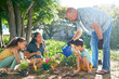 © Caia Image - Family planting and watering flowers in sunny summer garden