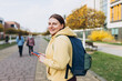 © mdyn - Image of young woman outdoors on the street looking aside chatting by mobile phone. Young women with backpack using smartphone at the city. Urban lifestyle concept.
