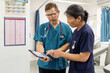 © Austockphoto - Man and woman health care workers standing together while looking on a tablet in the clinic